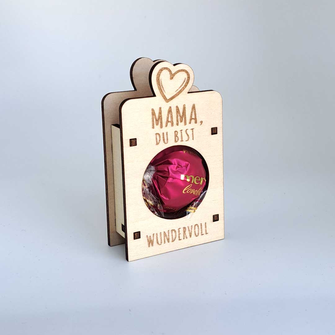 Produkt: Taschenähnliche Form mit Aussparung für eine Schokopralinenkugel. Eingravierter Text: 'Mama, du bist wundervoll'